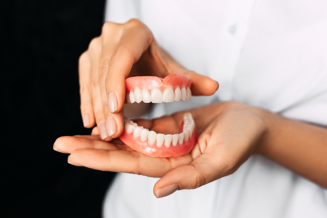 The dentist is holding dentures in his hands. Dental prosthesis in the hands of the doctor close-up. Front view of complete denture. Dentistry conceptual photo. Prosthetic dentistry. False teeth.